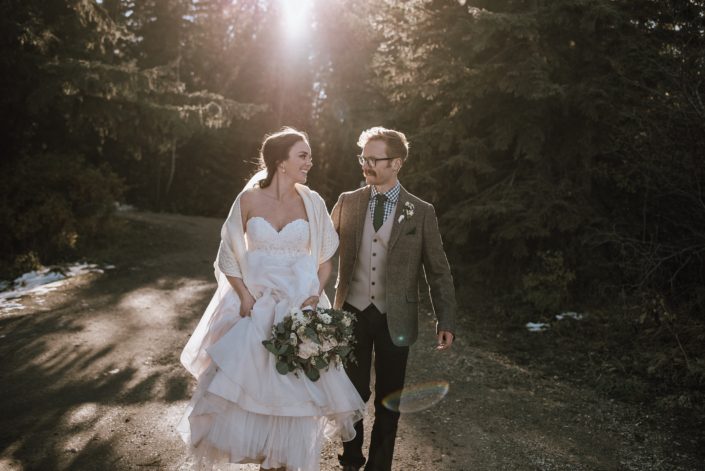Bride in blush dress with shawl with groom in tweed at a fall wedding with a white bouquet with eucalyptus