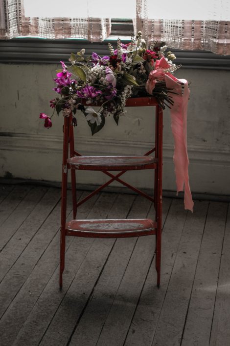 Pink Vintage Photoshoot - White, pink and purple wildflower bouquet made of cosmos and greenery tied with trailing ribbons atop a red ladder.