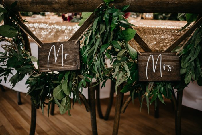 Rustic Boho Chic Wedding - Mr and Mr signs hanging from chair backs draped with garlands made of greenery.