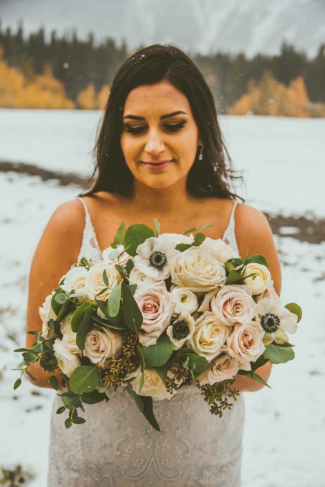 Our bride Meagan holding a gorgeous hand-tied bouquet made of panda anemones, white ranunculus, ivory playa blanca roses, blush pink quicksand roses, and eucalyptus greenery.