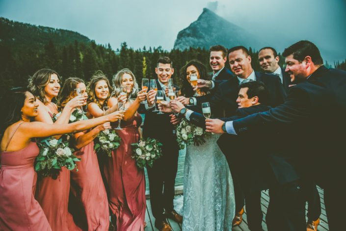 Meagan and Dwayne's bridal party toasting with champagne. Blush and Mauve Canmore Wedding