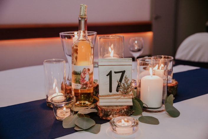 Centrepiece for Brooke and Levi's Rustic Chic Blush Wedding. Created with pillar candles, tree cookies, white painted table numbers, and eucalyptus leaves.