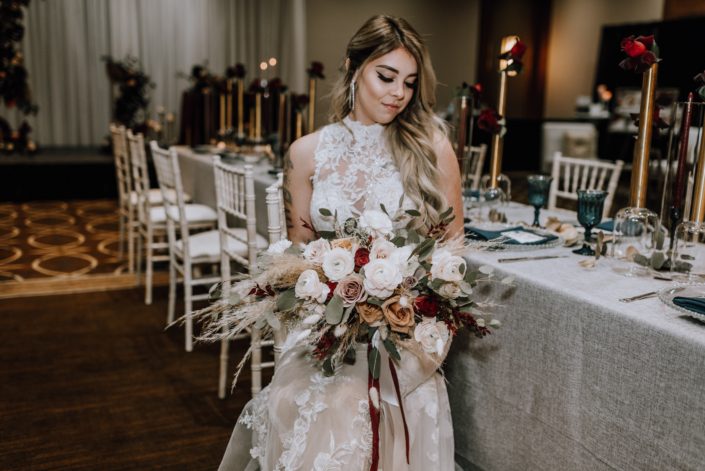 Cambridge Bridal Show 2020 - Bride wearing lace dress and holding bridal bouquet of pampas grass, blush and red roses, blush ranunculus and eucalyptus greenery with trailing ribbon.