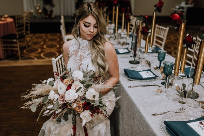 Cambridge Bridal Show 2020 - Bride wearing lace dress and holding bridal bouquet of pampas grass, blush and red roses, blush ranunculus and eucalyptus greenery with trailing ribbon.
