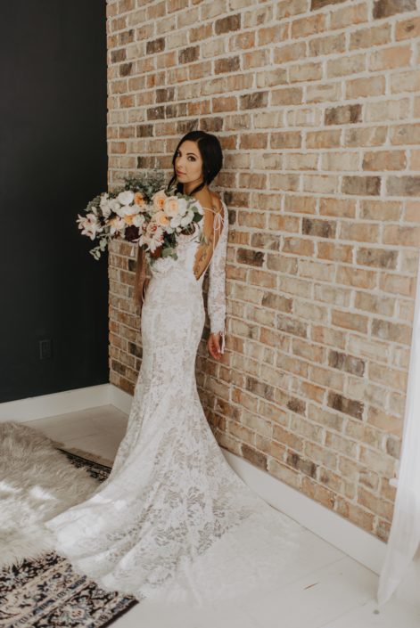 Neutrals Styled Shoot with Down the Aisle - Bride wearing lace gown holding a neutral coloured bouquet with ivory flowers and greenery tied with trailing ribbons.