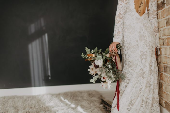 Neutrals Styled Shoot with Down the Aisle - Neutral coloured bridal bouquet with orchids, roses, magnolia leaves and eucalyptus greenery tied with trailing ribbons.