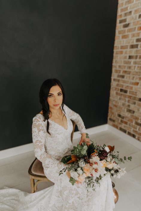 Neutrals Styled Shoot with Down the Aisle - Bride wearing lace gown holding neutral bouquet of orchids, roses, magnolia leaves and eucalyptus greenery.