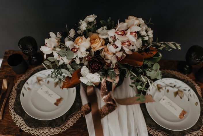 Neutrals Styled Shoot with Down the Aisle - Neutral coloured bridal bouquet with peach roses, orchids, magnolia leaves and eucalyptus greenery tied with trailing ribbon atop a decorated sweetheart table.