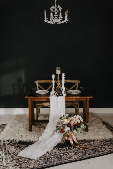 Neutrals Styled Shoot with Down the Aisle - Neutral coloured bridal bouquet with roses, orchids, magnolia leaves and eucalyptus greenery tied with trailing ribbons next to a decorated sweetheart table.