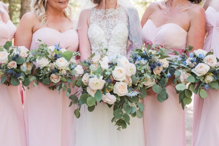 Close up of Amy and her bridesmaids' pink and blue bouquets designed with white o'hara garden roses, quicksand roses, ranunculus, delphinium, astilbe, eryngium and eucalyptus.