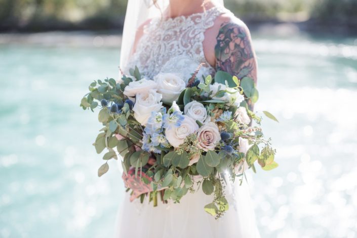 Amy's pink and blue bridal bouquet designed with white o'hara garden roses, quicksand roses, ranunculus, delphinium, astilbe, eryngium, and eucalyptus.
