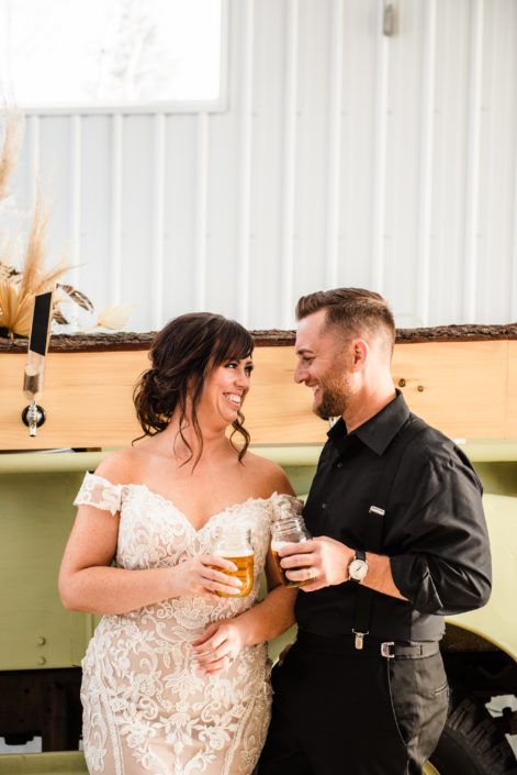 Bride and groom with mason jars of beer in front of the Prohibition Pickup taps.