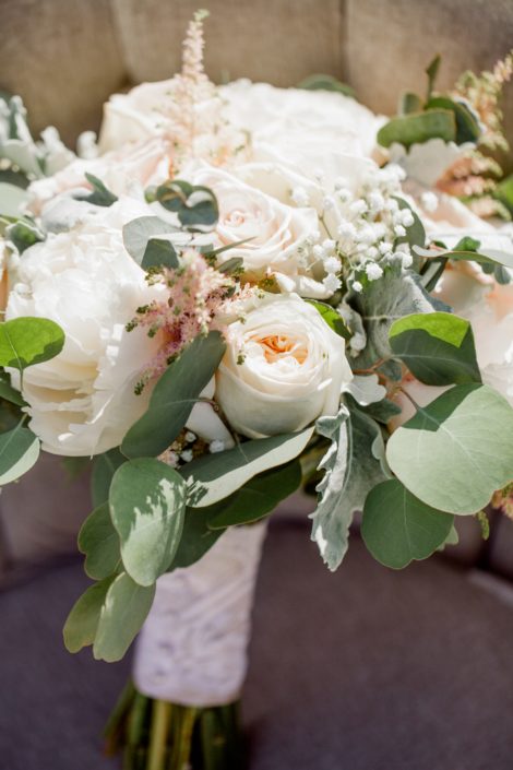 Close-up of Kuera's cream and blush vintage chic bridal bouquet featuring white o'hara garden roses, white peonies, quicksand roses, pale pink astilbe, babies breath, dusty miller and eucalyptus greenery.