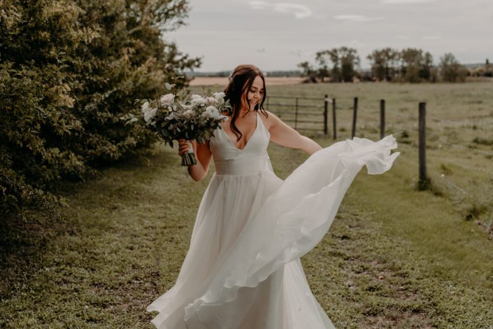 Bride Erika twirling her white bridal gown and carrying a blush, ivory and white bridal bouquet with fresh eucalyptus greenery.