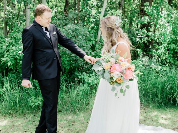 Griffin and Taylor holding coral charm peony bouquet with monstera leaves, boston fern, and eucalyptus.