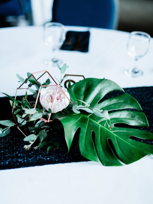 Centrepiece made of monstera leaf, blush peony, and a mixed variety of eucalyptus in a metallic geometric display.