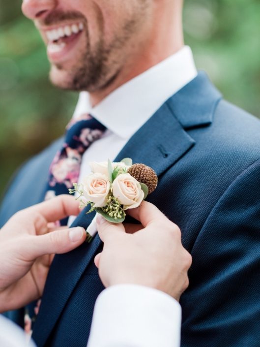 Groom getting his dusty rose boutonniere attached.