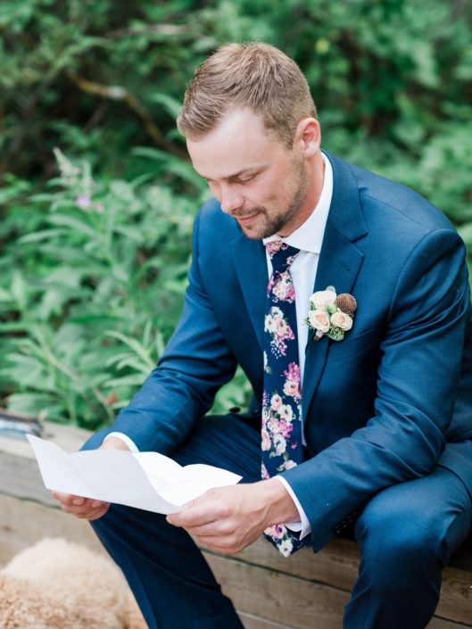 Groom reading message from the bride wearing a rustic yet elegant dusty rose boutonniere.