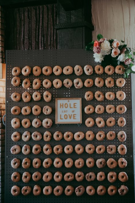 Doughnut wall with letter board and a corner coral, blush and ivory floral arrangement.