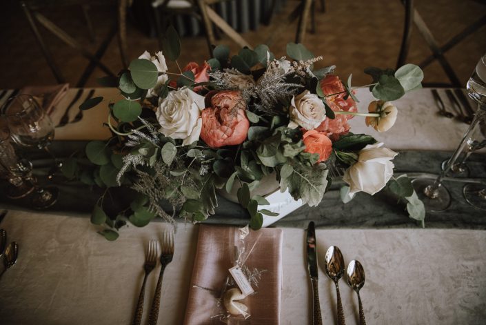 Centrepiece and table setting for Canyon Ski Resort Open House 2019. Arrangement was designed with playa blanca roses, quicksand roses, peach ranunculus, coral charm peonies, pale pink astilbe, silver painted plumosa and a mixed variety of eucalyptus greenery.