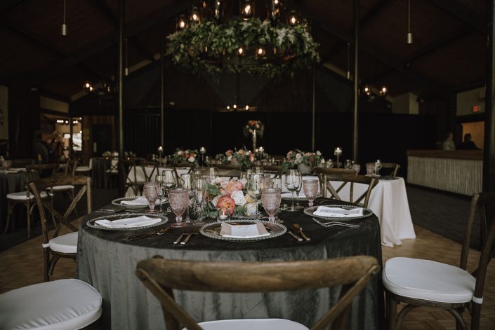 Canyon Ski Resort Open House 2019 tablescape featuring charcoal grey linens, clear and blush table settings, and a blush and coral floral arrangement with silver metallic and greenery accents.