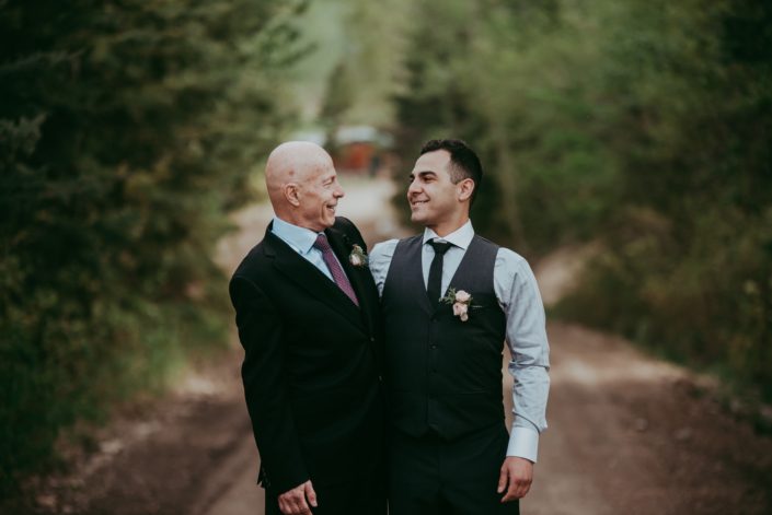 Groom and son wearing blush spray rose boutonnieres accented with burgundy ninebark leaves and juniper.