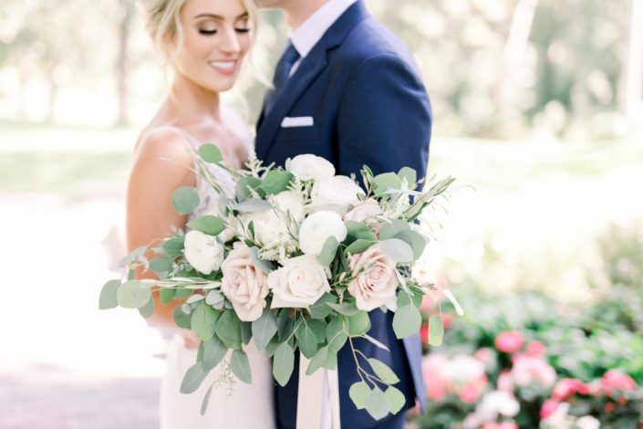 Kayla's timeless white wedding bridal bouquet designed with white o'hara garden roses, white ranunculus, quicksand roses, olive branches, and fresh eucalyptus.