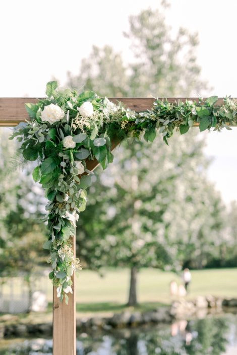 Corner archway arrangement on a wooden archway designed with white Tibet roses, a mixed variety of eucalyptus, italian ruscus, salal and plumosa.