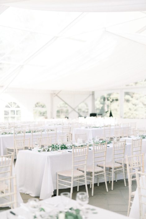 Simple white reception venue accented by garlands of fresh greenery including eucalyptus and Italian ruscus.
