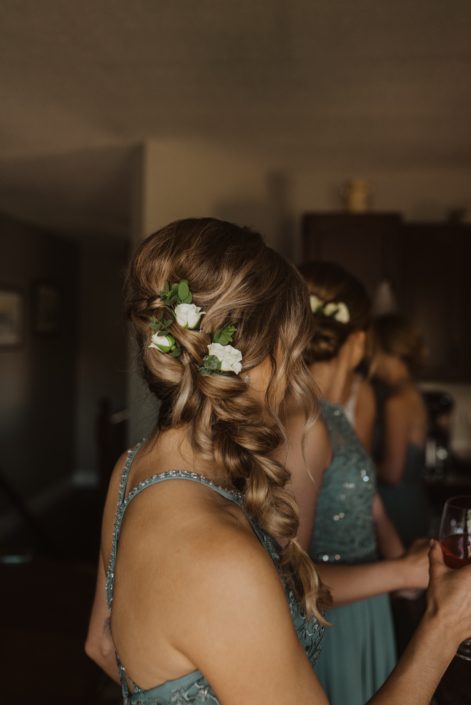 Bridesmaid hair flowers; white spray roses tucked into braided hair.