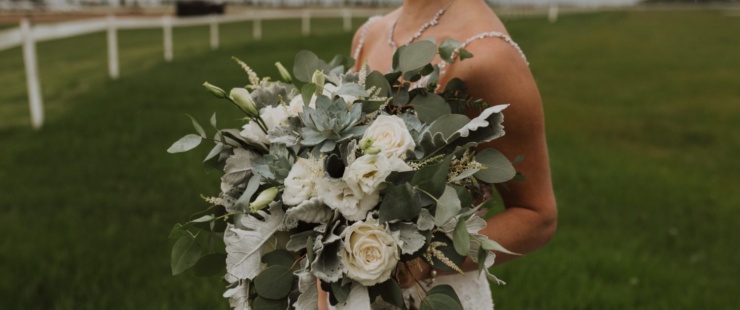White and grey green bridal bouquet with a vintage feel designed with Playa Blanca roses, lisianthus, blue star succulents, astilbe, dusty miller, and a variety of eucalyptus greenery.