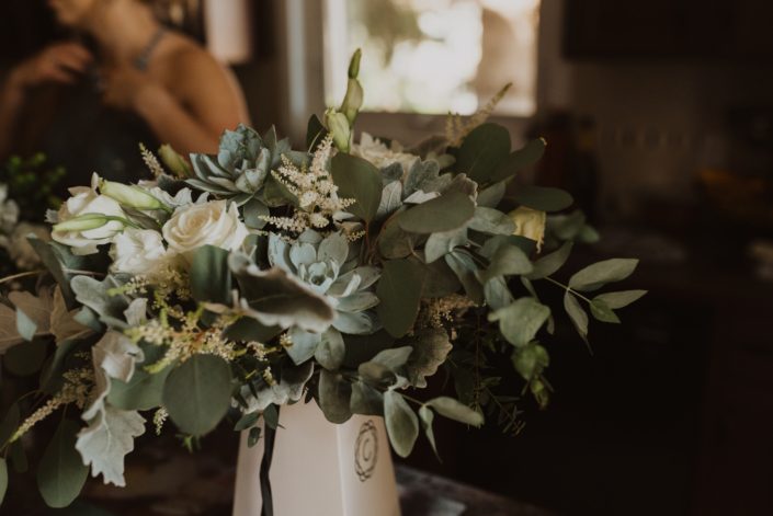 Bridal bouquet featuring white Playa Blanca roses, white lisianthus, white astilbe, blue star succulents, dusty miller and a mixed variety of eucalyptus greenery.
