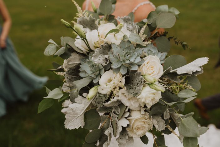 Vintage inspired bridal bouquet designed with white Playa Blanca roses, white lisianthus, white astilbe, Blue Star succulents, dusty miller, and a mixed variety of eucalyptus.