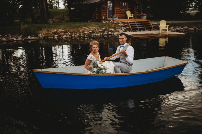 Bride and groom in a canoe in front of cabin at Pine and Pond.