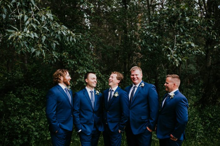Groom and groomsmen wearing navy suits and classic white boutonnieres.
