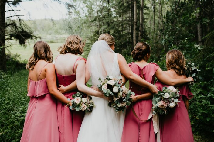 Briana and Mark's Glam Jewel Tone Wedding - Bride and bridesmaids with their backs to the camera holding jewel tone bouquets featuring roses, dahlias, ranunculus, scabiosa, astilbe and eucalyptus greenery.