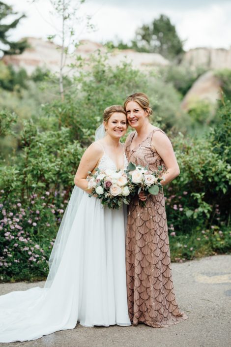 Bride and maid of honour holding romantic blush hand-tied bouquets designed with white ranunculus, quicksand roses, white o'hara garden roses, light pink astilbe and eucalyptus greenery.