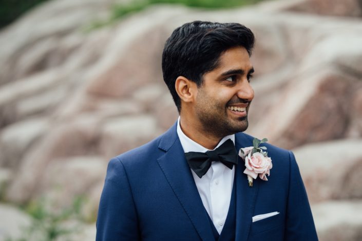 Groom, Jason, wearing a navy suit and blush boutonniere made with spray roses and eucalyptus.