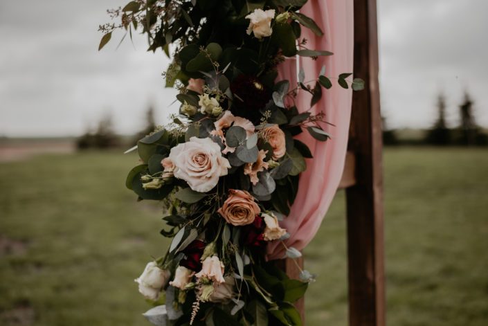 Archway garland for Crystal and Chance's Sweet Haven Barn Wedding designed with light pink astilbe, burgundy dahlias, cappuccino roses, quicksand roses, salal and eucalyptus.