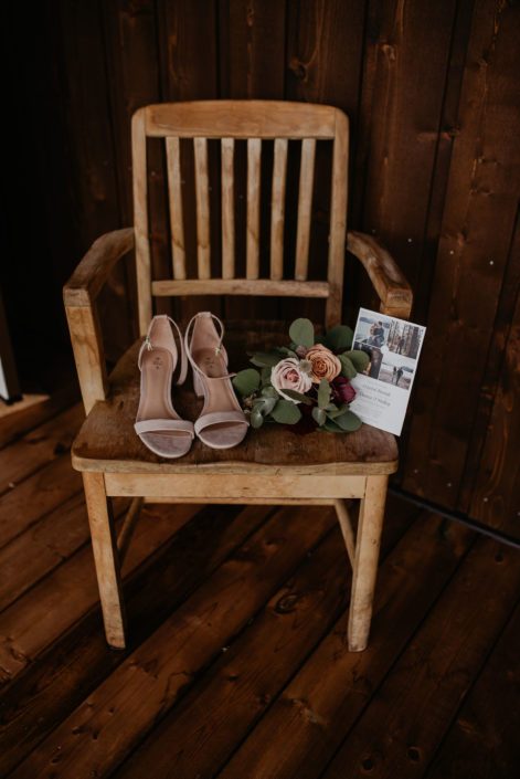 Bride's shoes, wedding invite and a small bouquet atop a chair.