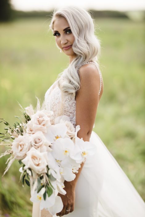 Boho Glam Bride with cascading bouquet featuring Phalenopsis orchids, quicksand roses, pampas grass, olive branches and silver dollar eucalyptus.