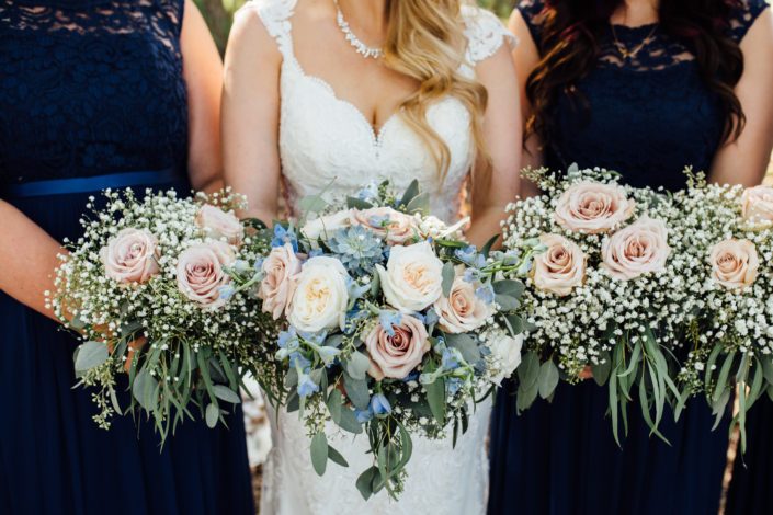 Bride and bridesmaids bouquets featuring quicksand roses, white o'hara garden roses, blue delphiniums, succulents, babies breath (gypsophila), and a mixed variety of eucalyptus greenery including feather, gunni, seeded and silver dollar.