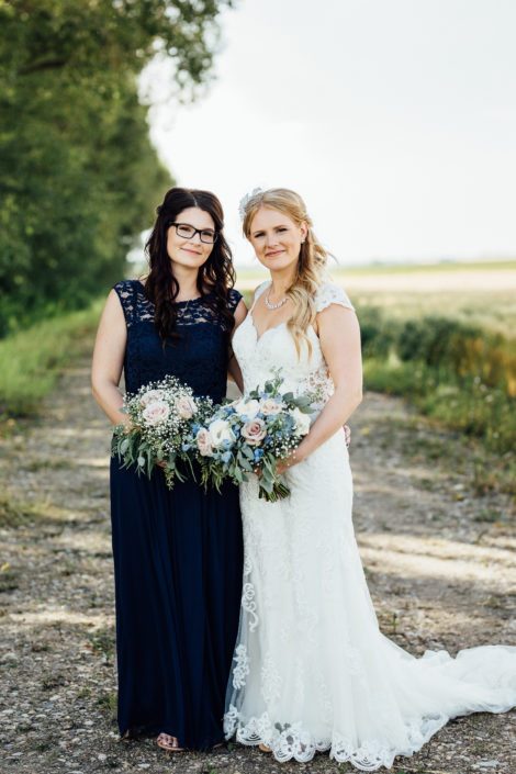 Bride, Kelsie, and bridesmaid with bouquets made of quicksand roses, white o'hara garden roses, succulents, babies breath, blue delphiniums, and eucalyptus greenery.