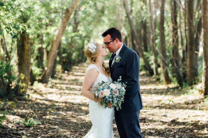 Kelsie and Kyle's Blush and Blue Vintage Barn Wedding - Bride and groom, Kelsie and Kyle, with blush and blue bridal bouquet and boutonniere featuring delphiniums, quicksand roses, white o'hara garden roses, gypsophila and a mixed variety of eucalyptus greenery.