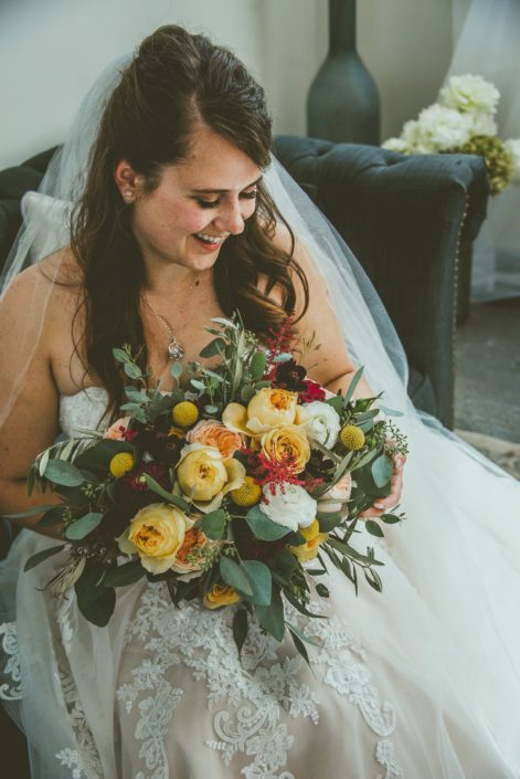 Bride, Bianca, with mustard yellow bridal bouquet featuring golden mustard roses, caramel antike garden roses, juliet garden roses, white ranunculus, plum dahlias, billy balls, red astilbe, olive branches and eucalyptus.