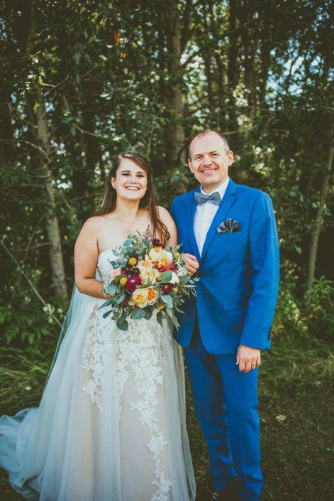 Bride and father of the bride with mustard yellow bridal bouquet with accents of ivory and burgundy flowers.
