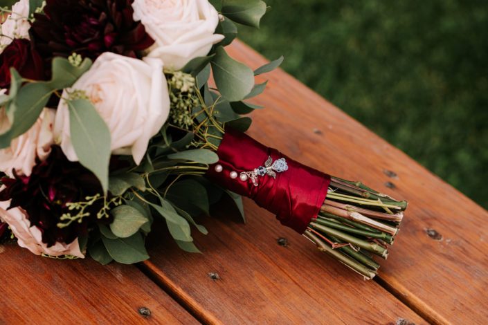 Bridal bouquet wrapped with burgundy satin and finished with bride's charm.