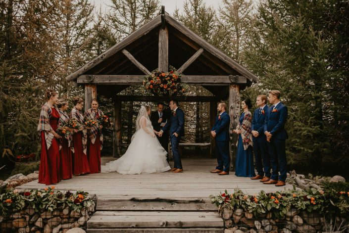 Hayley and James' rustic fall wedding ceremony featuring archway arrangement, garlands, bouquets and boutonnieres.