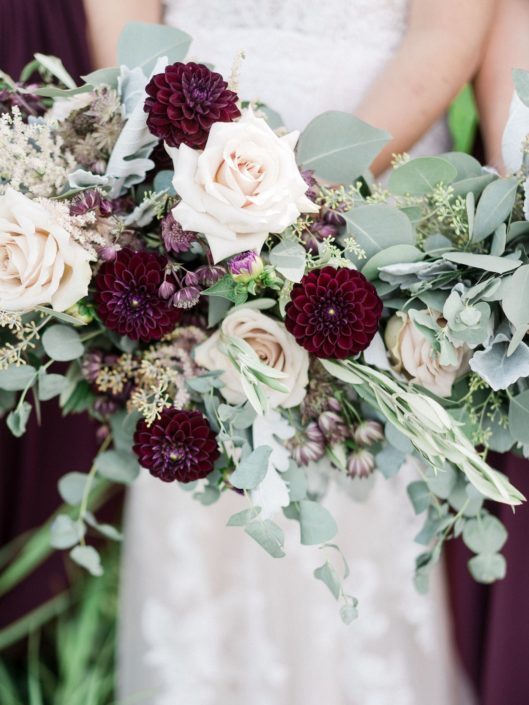 Burgundy country chic bridal bouquet designed with burgundy astrantia, astilbe, burgundy dahlias, brown lisianthus, quicksand roses, dusty miller, olive branches and various types of eucalyptus.