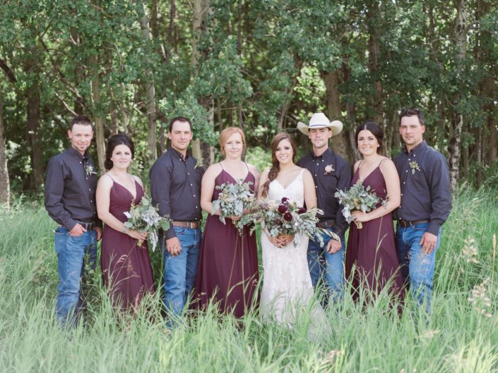 Country chic bridal party; bridesmaids in burgundy; cowboys; bride wearing lace and carrying a burgundy bouquet featuring quicksand roses and burgundy dahlias.